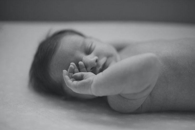 A baby is laying on the bed and smiling.