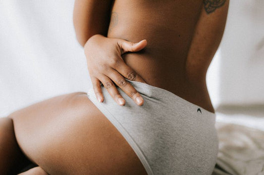 A woman in white underwear sitting on the ground.