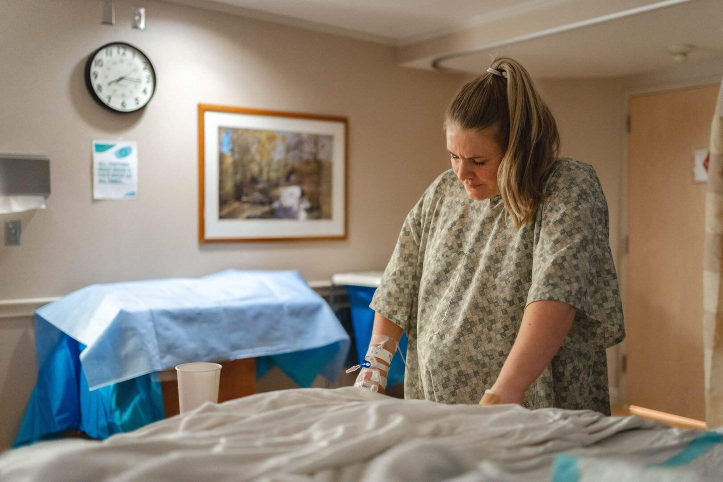 A woman in a hospital room setting up a bed.